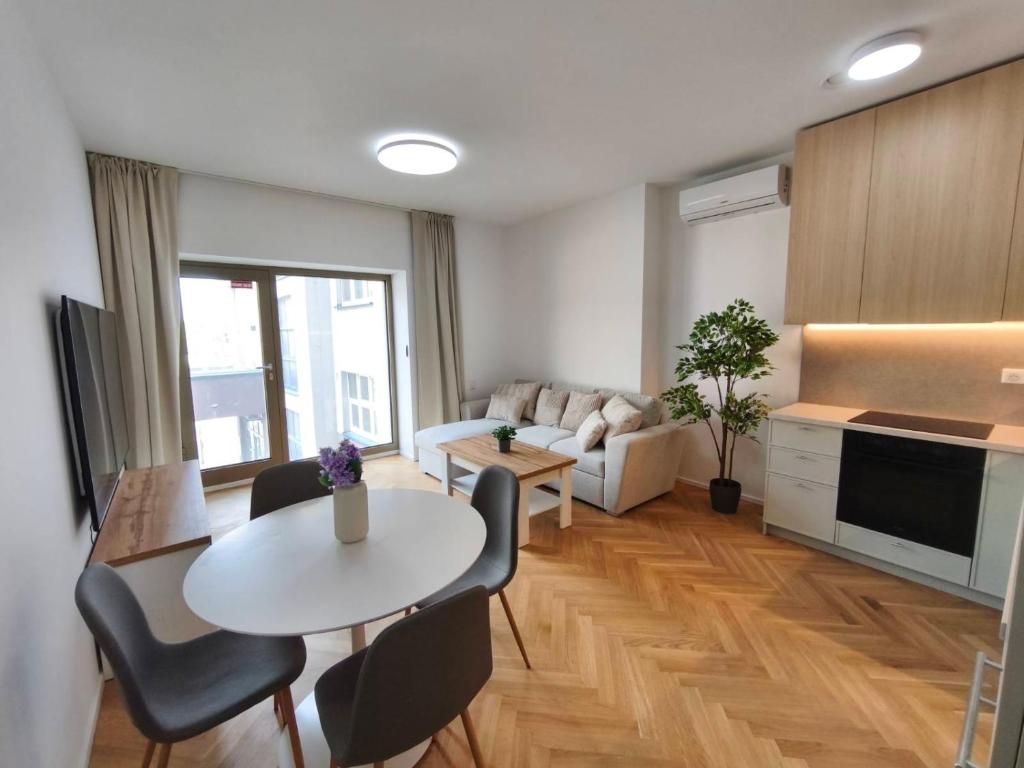 Bright living room with a dining table and herringbone parquet in a HEUHAUS apartment